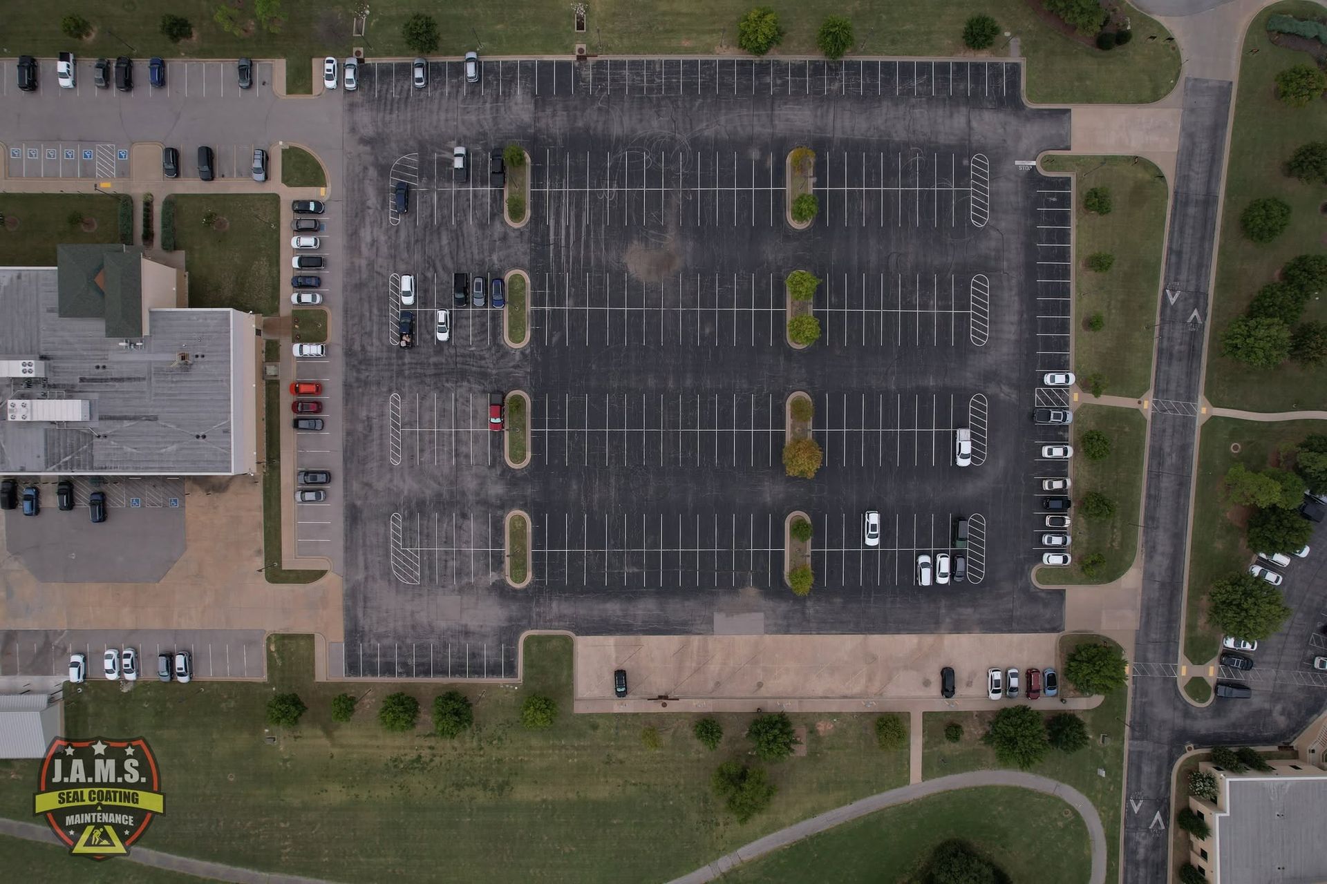 Aerial view of an almost empty parking lot beside a building and grassy areas
