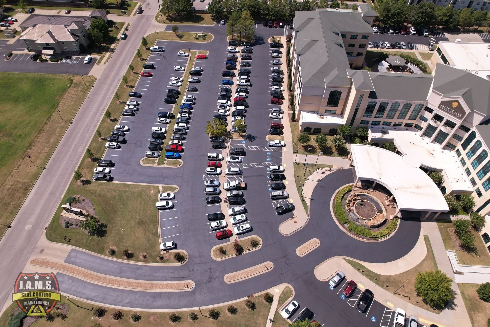 Aerial view of a hospital or office complex with a full parking lot and circular driveway.