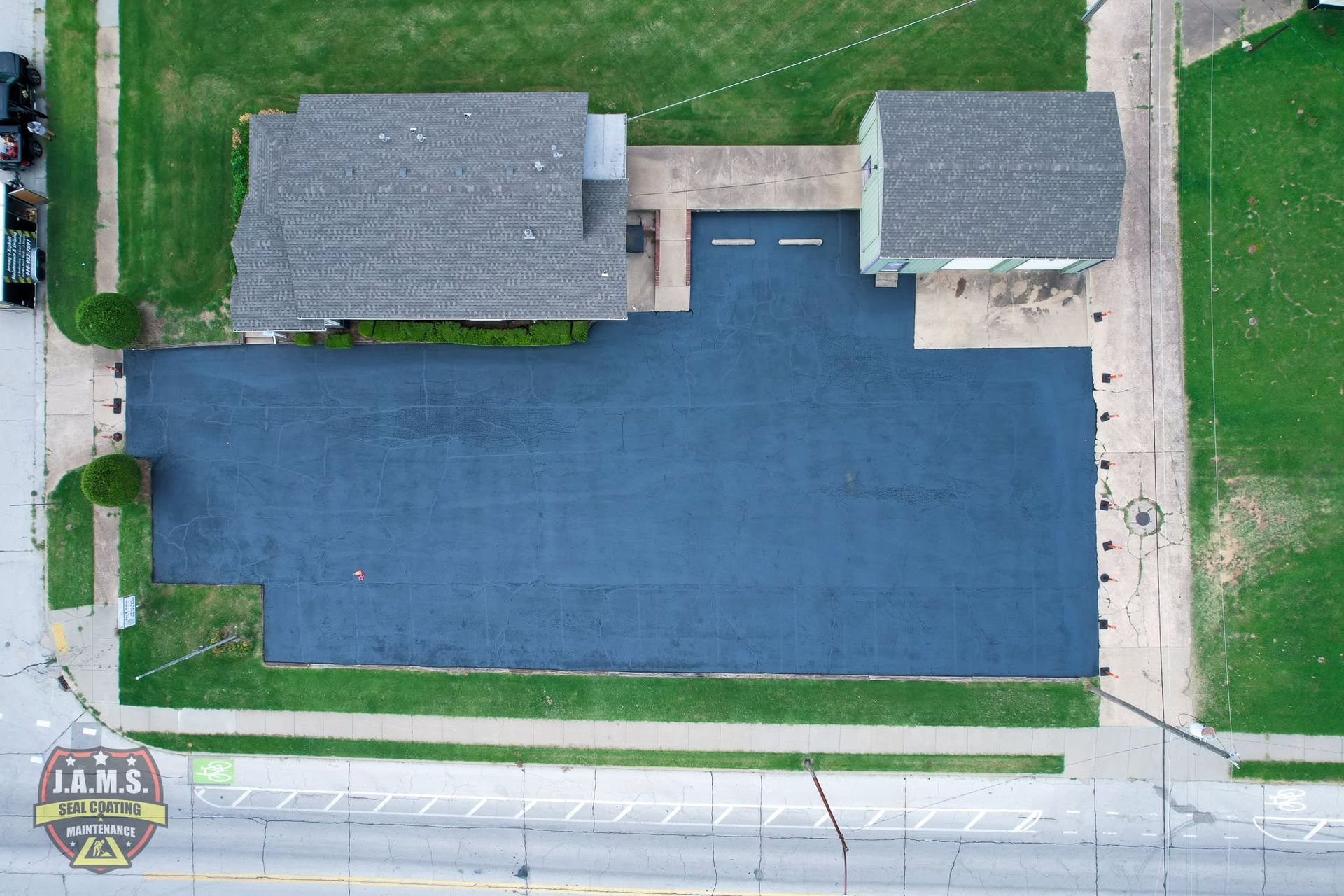 Aerial view of a large blue-roofed building beside two smaller gray buildings and a road.