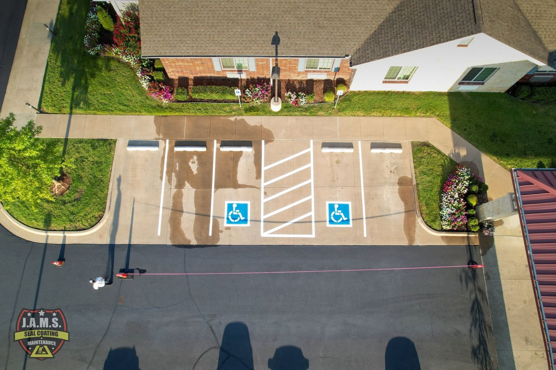 Overhead view of two accessible parking spaces outside a building, marked with blue wheelchair symbols.