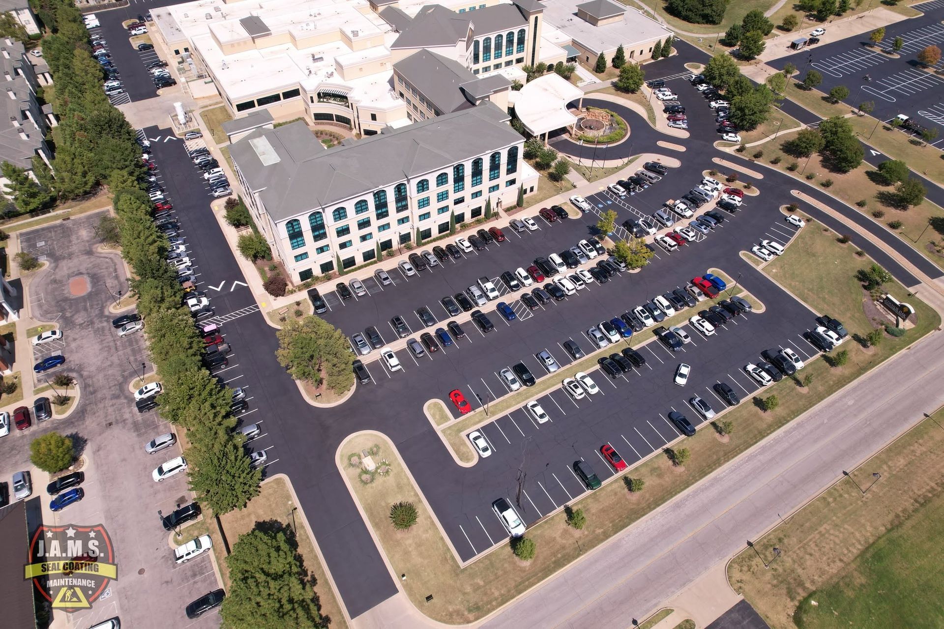 Aerial view of a large office building with parking lots, cars, and surrounding roads.