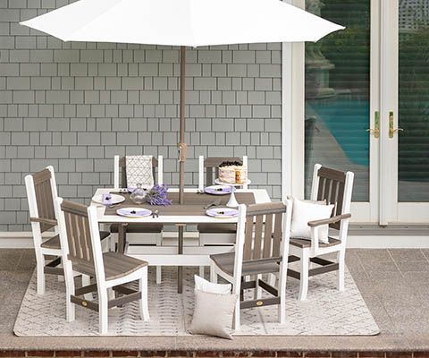 Patio dining set: white and gray table, chairs, umbrella, gray shingles background.