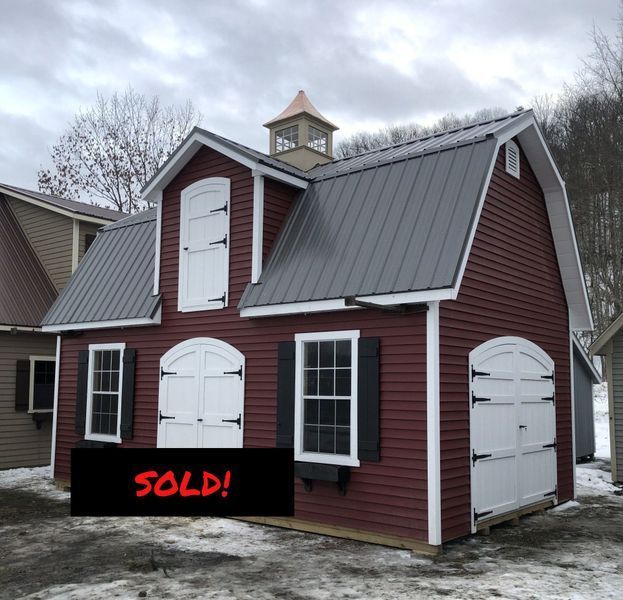 Red barn with white trim, black shutters, and a gray metal roof;