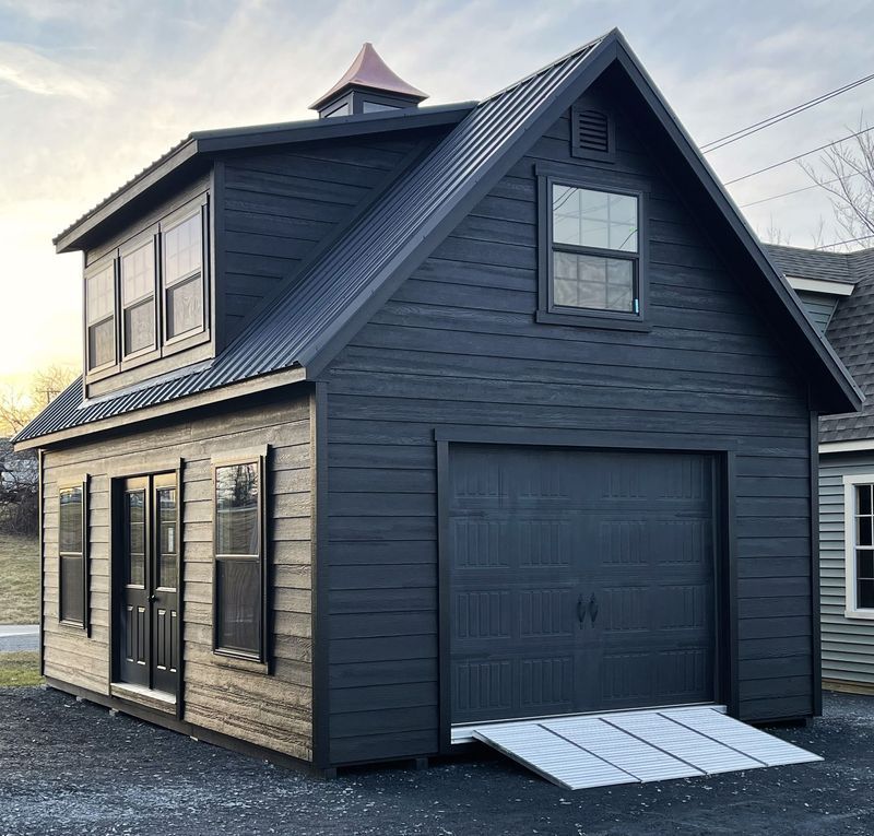 Black two-story garage with ramp, small window, and double doors.