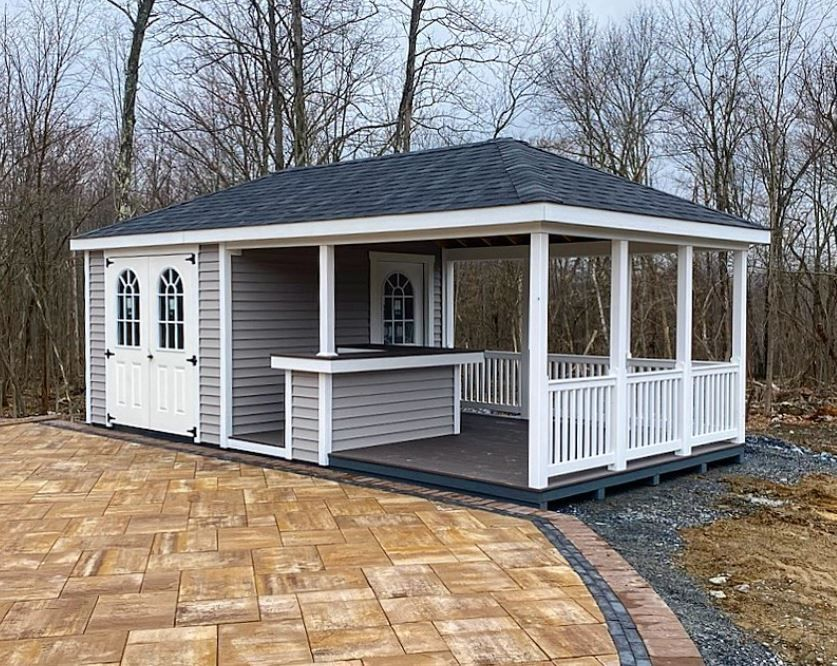 Green and white screened porch shed with black railing, on grass, with a small cupola.