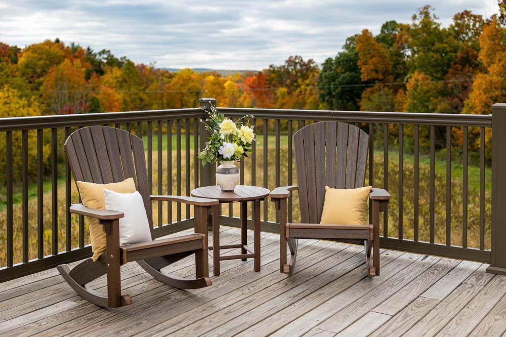 Wooden rocking chairs and small table on deck, overlooking autumn foliage.