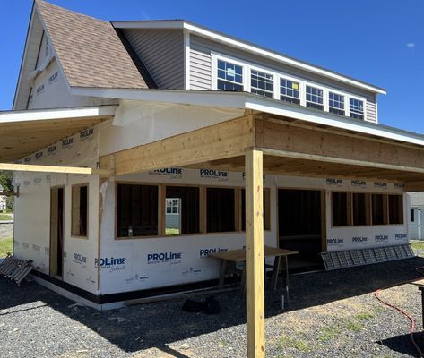 Building exterior under construction with exposed wood framing and blue sky.