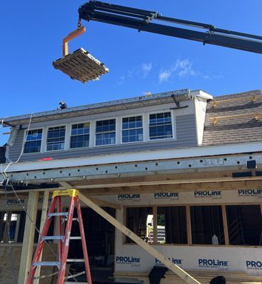 A crane lifting a pallet of materials onto a roof during construction.