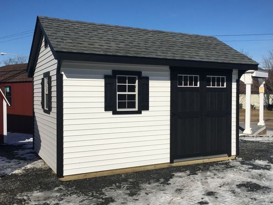Small white shed with black trim and door; gray roof.