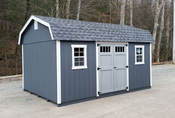 Gray shed with barn-style roof and double doors, white trim around doors and windows.