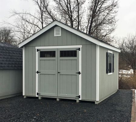 Gray shed with double doors, white trim, black hardware, and small window.