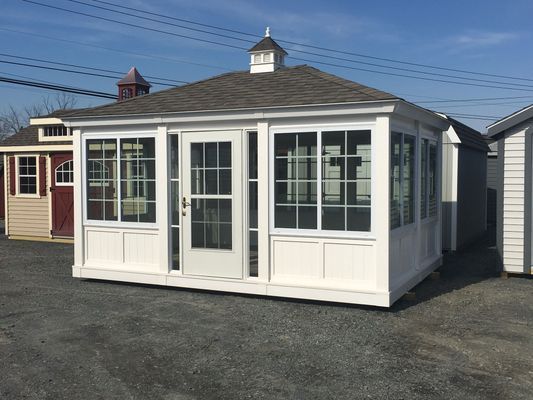 White gazebo with glass windows and door, gray roof, and small cupola; outdoors.