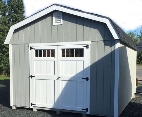 Gray and white barn-style shed with double doors, a black roof, and white trim.