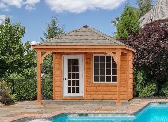 Wooden pool house with door and window next to a pool, under a blue sky.
