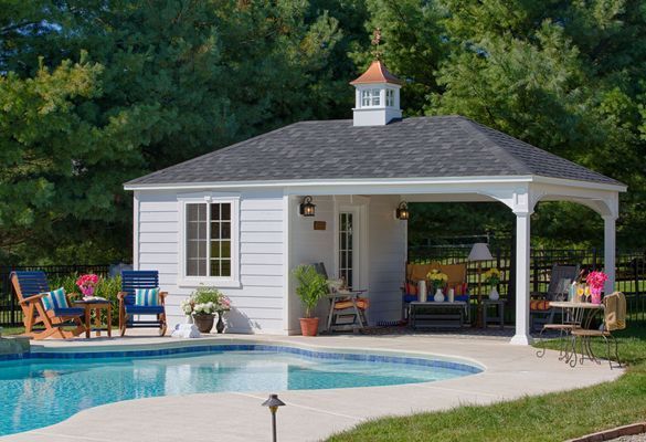 Poolside gazebo with seating area and small storage room, next to a blue swimming pool.