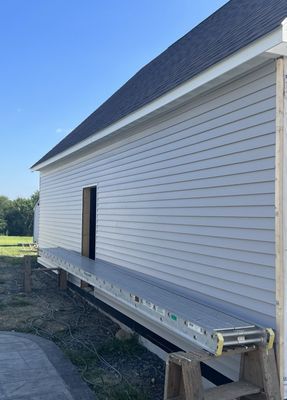 Exterior of a building with grey siding and a temporary work platform against it.