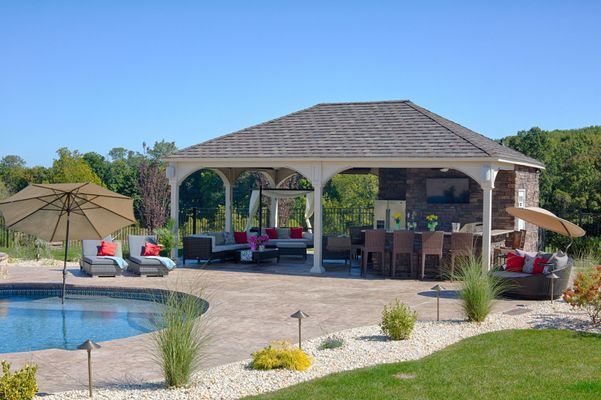 Outdoor bar and lounge area next to a pool. Brown and white structure with seating and umbrellas.