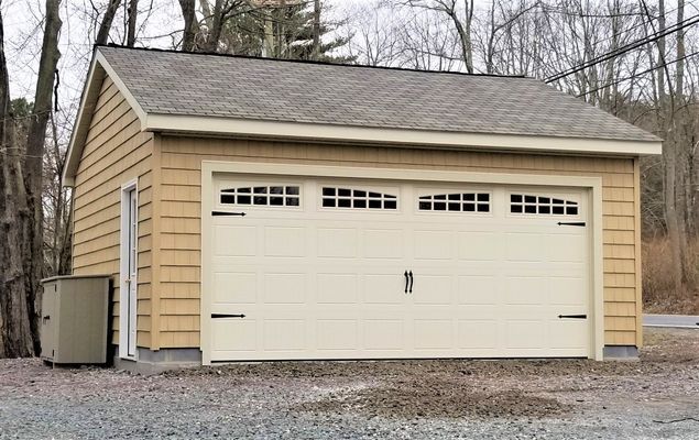 Beige garage with light-colored door and tan siding, set on gravel driveway.