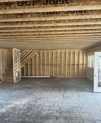 Interior of a new construction garage. Concrete floor, wood-framed walls, staircase to second level.