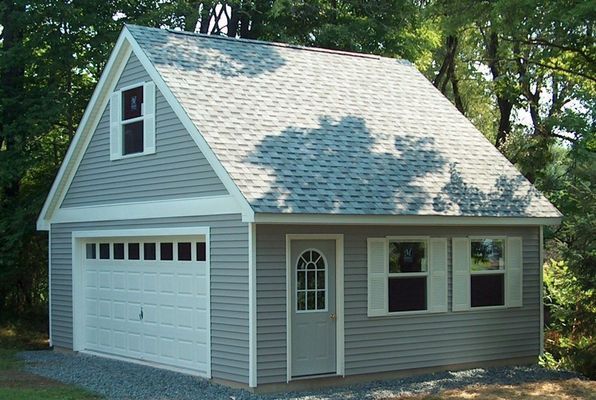 Grey garage with white trim, door, garage door, and shutters, and gray roof.