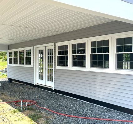 Gray house exterior with white-framed windows and French doors under a white covered porch.