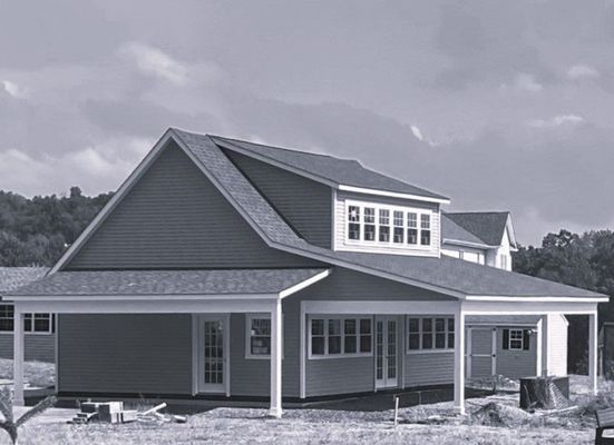 House under construction with light siding, a porch, and a second-story section with multiple windows.
