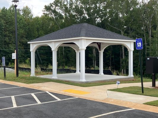 White gazebo with dark roof, gray concrete floor, and blue handicap sign.