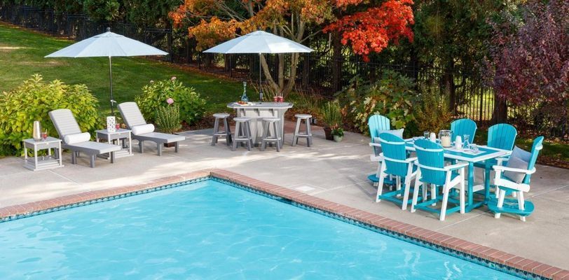 Poolside outdoor scene: pool, chaise lounges, bar set, dining table and chairs with umbrellas.