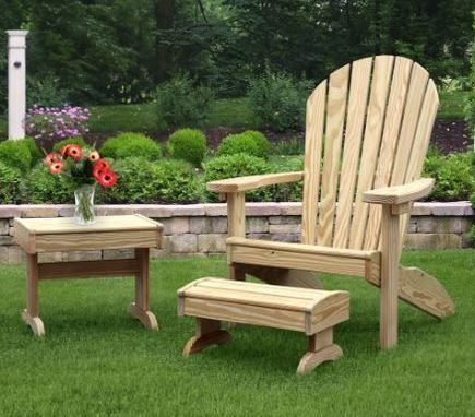 Wooden Adirondack chair, footstool, and side table on a lawn, with a vase of flowers.