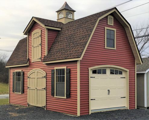 Red and tan barn-style shed with a cupola and garage door.