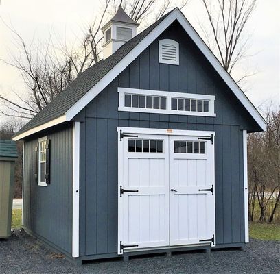 Blue shed with white doors, trim, and windows. Cupola on the roof.