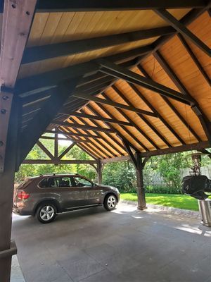 Gray SUV parked under a wooden carport with a dark roof.
