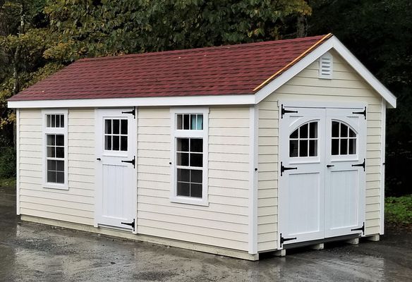 Tan shed with red roof, white doors and windows, and dark hinges.