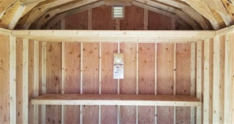 Interior of a wooden shed with shelving. Wooden walls and ceiling, a small vent.