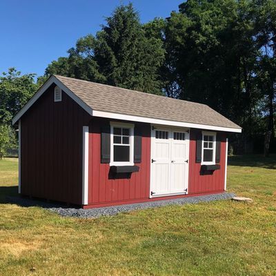 Red shed with white trim, windows, and doors; sitting on a grassy lawn.