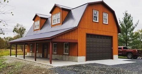 Orange barn-style building with a porch and garage door. Gray metal roof. A red truck is parked to the side.