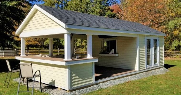 Yellow shed with bar, columns, and serving window, brown roof, grass setting.