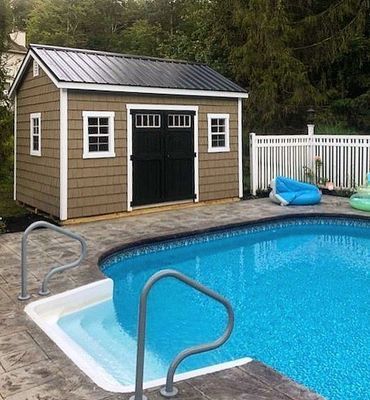 Poolside shed with a black metal roof, brown siding, and a black double door.