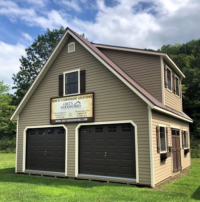 Two-story tan garage with brown doors and roof, sign 