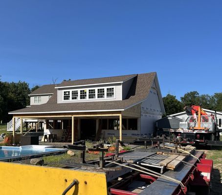 House under construction, a pool, and a crane on a sunny day.