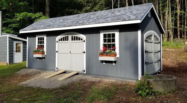 Gray shed with gray roof, white trim, and flower boxes; ramp leads to garage door.