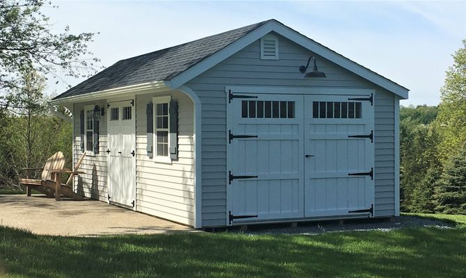 Light blue and white garage-style shed with double doors and window, gray roof, and green lawn.