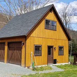Two-story wooden building with brown garage doors, a brown door, and two windows.