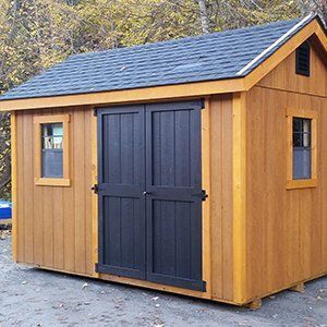 Wooden storage shed with black double doors, small windows, and blue roof.