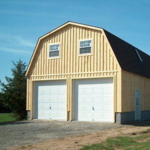Two-car garage with light yellow siding, white doors, and a black roof against a blue sky.