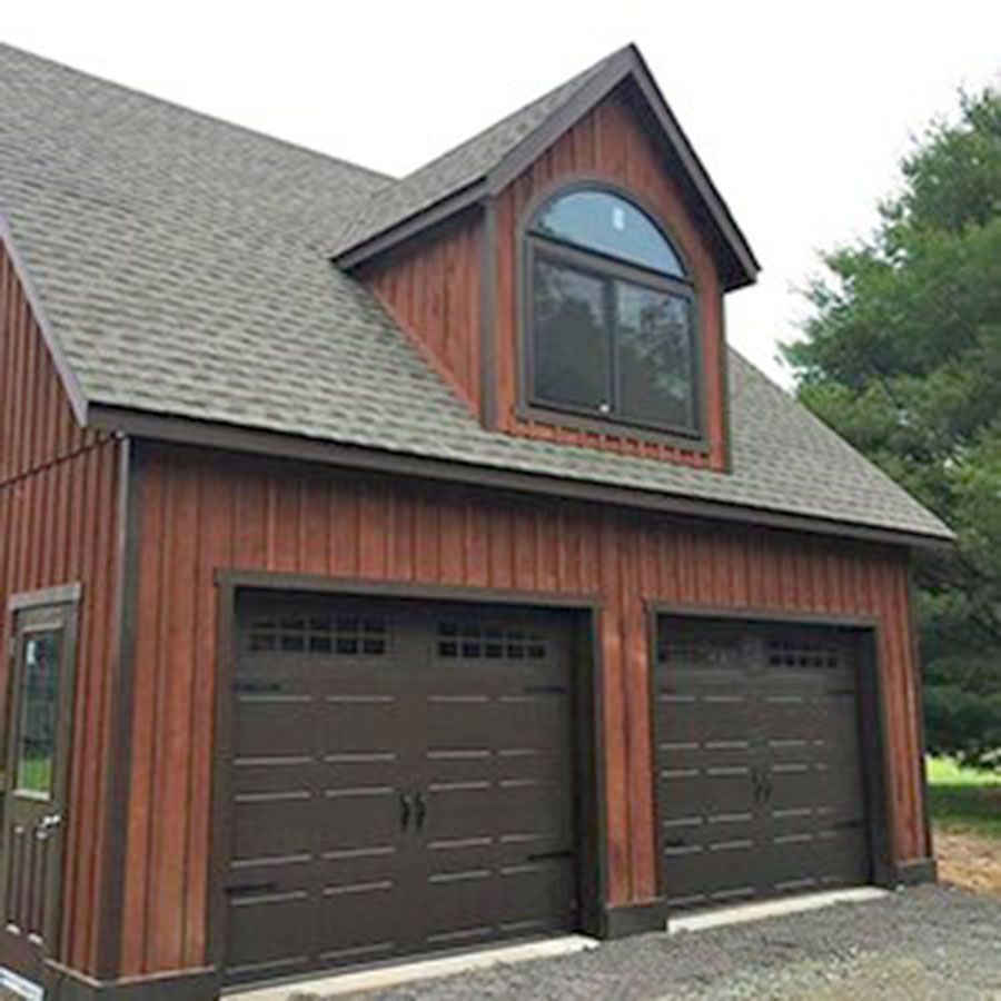 Brown garage with two doors, an arched window, and a wood-paneled facade.