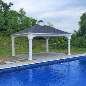 White gazebo by a blue swimming pool, with a dark gray roof and surrounding greenery.