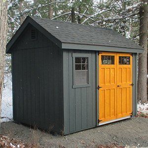 Gray shed with bright orange doors and a small window in a snowy forest.