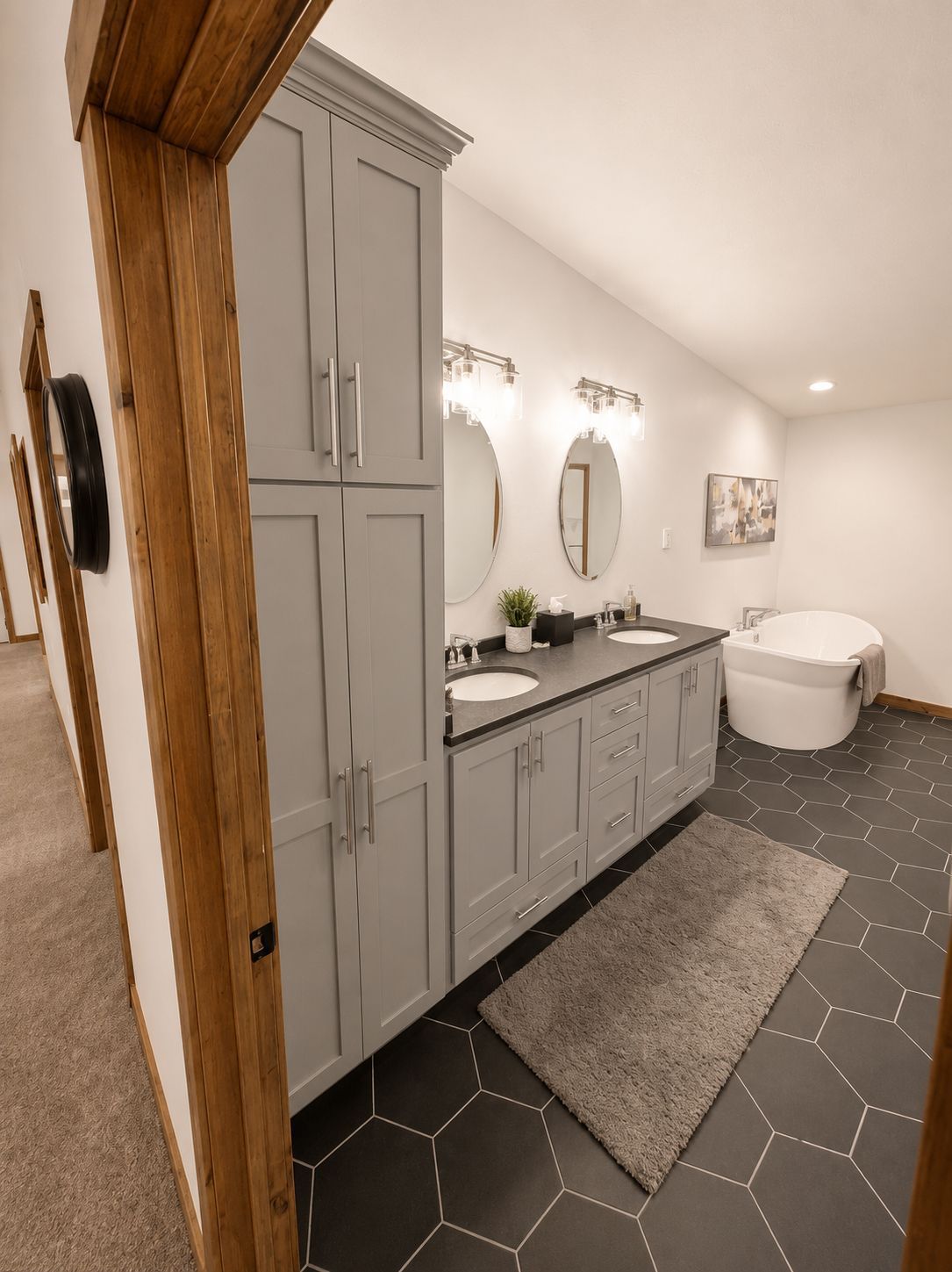 Modern bathroom with gray cabinets, double sinks, and oval mirrors