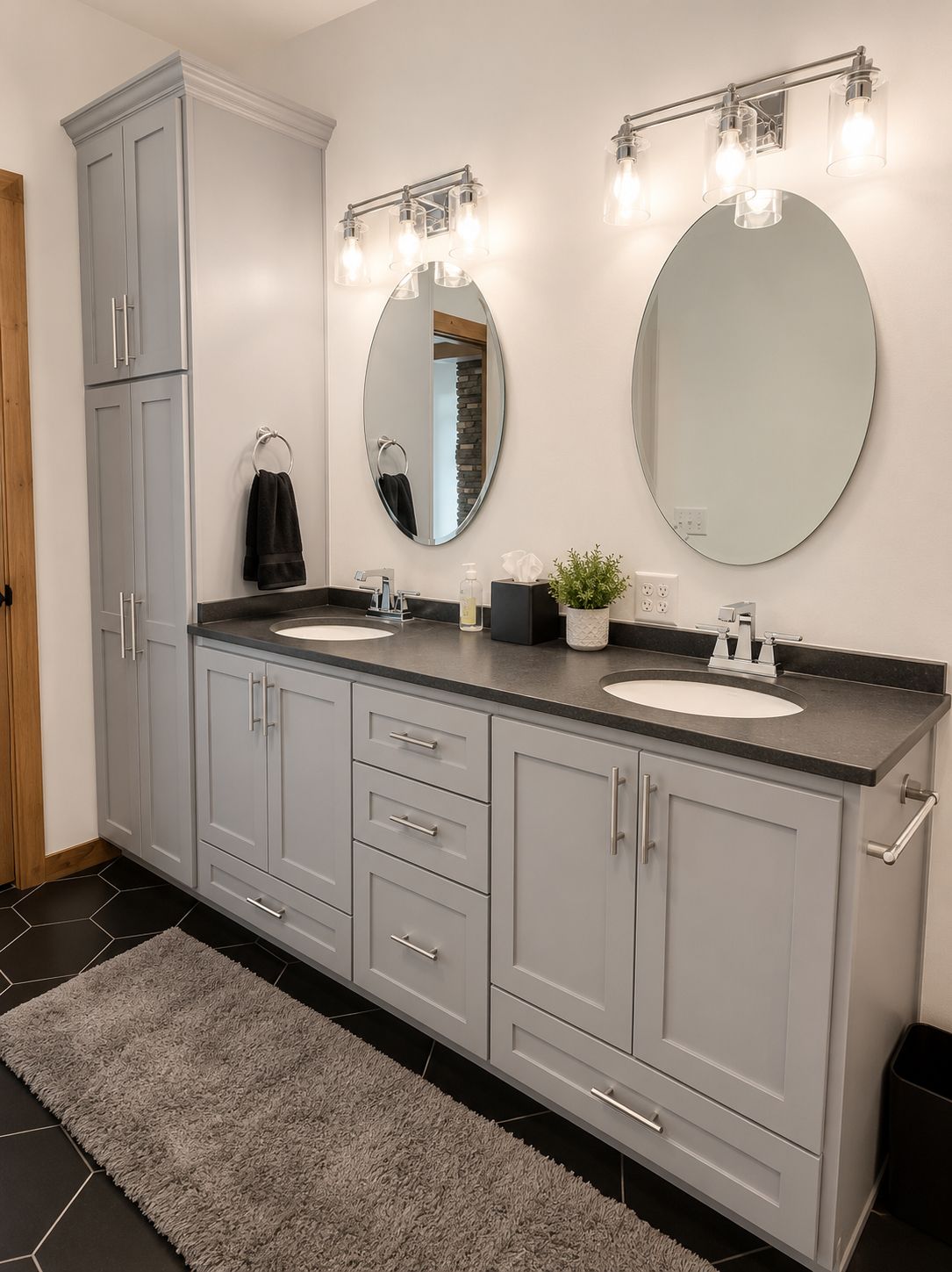 Bathroom vanity with gray cabinets, two oval mirrors, and wall sconces 